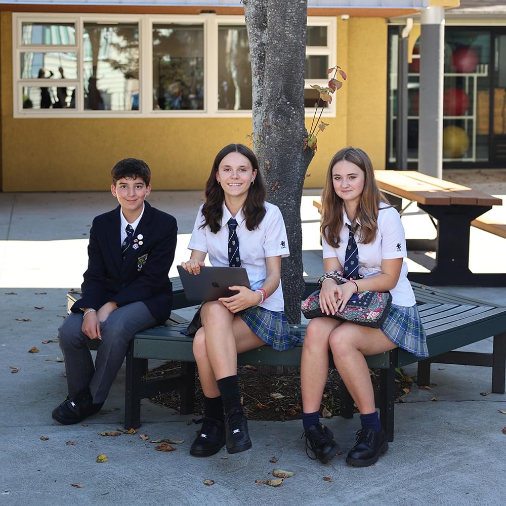 Three Senior School students sitting under a treet